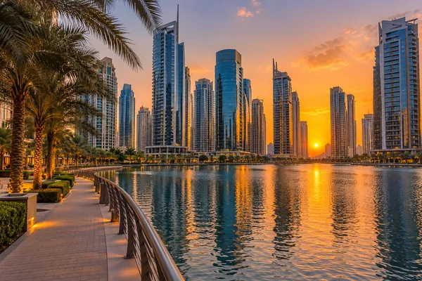 AI-generated illustration of lakeside towers and a palm-lined walkway at sunset